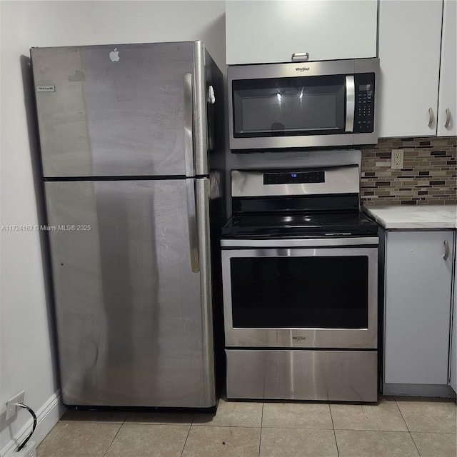 kitchen with light tile patterned floors, light countertops, appliances with stainless steel finishes, and white cabinets