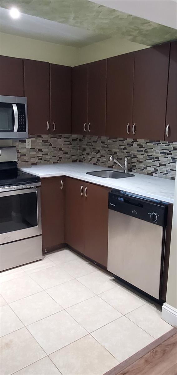 kitchen with decorative backsplash, dark brown cabinets, stainless steel appliances, and sink