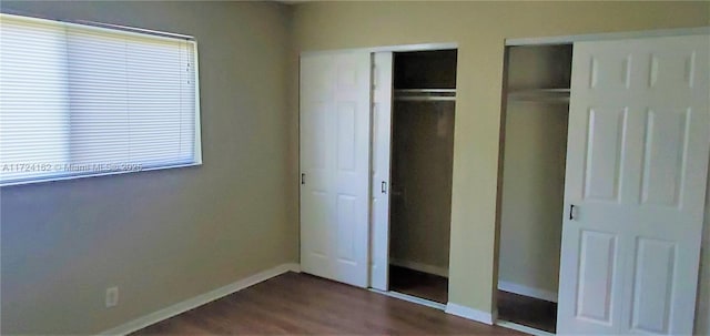 unfurnished bedroom featuring wood-type flooring and multiple closets