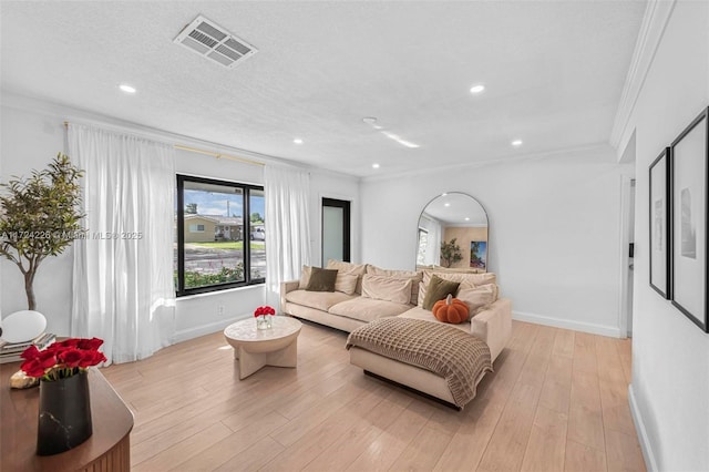 living room with crown molding, a textured ceiling, and light wood-type flooring