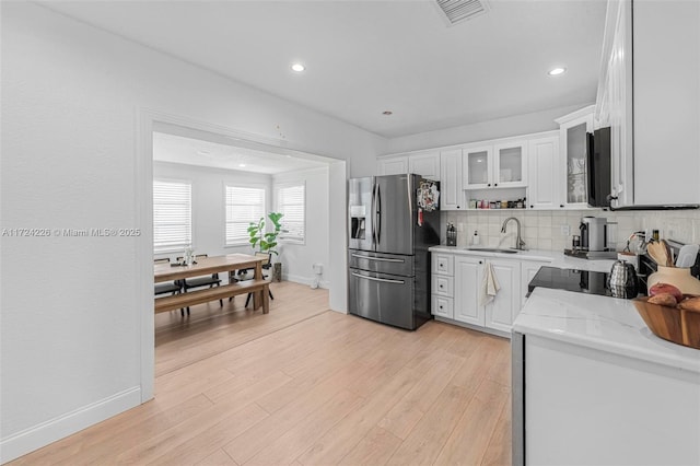 kitchen featuring stainless steel fridge, tasteful backsplash, sink, white cabinets, and light hardwood / wood-style floors