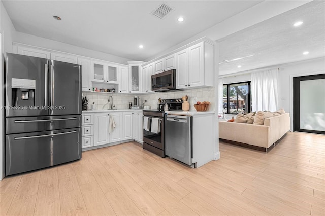 kitchen featuring sink, stainless steel appliances, tasteful backsplash, light hardwood / wood-style floors, and white cabinets