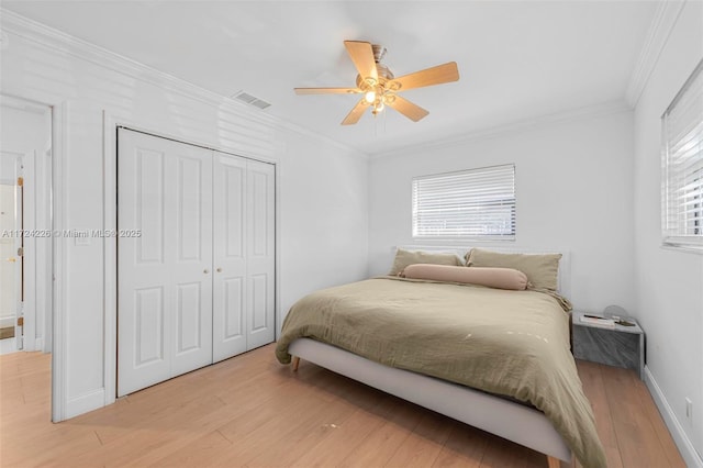 bedroom featuring ceiling fan, a closet, crown molding, and light hardwood / wood-style flooring