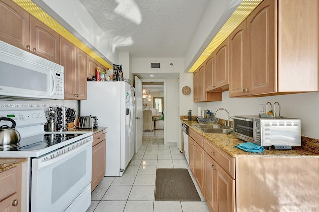 kitchen with a textured ceiling, light tile patterned floors, sink, and white appliances