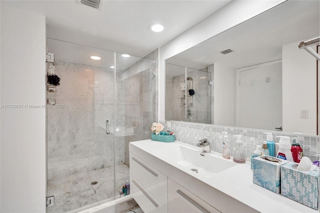 bathroom with decorative backsplash, tile walls, vanity, and a shower with door