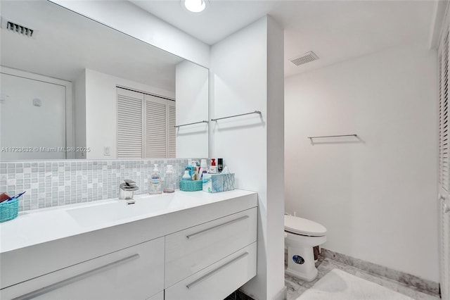 bathroom featuring tasteful backsplash, vanity, and toilet