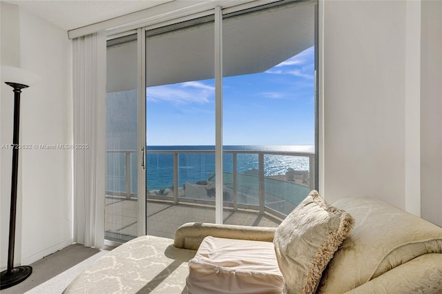 bedroom featuring carpet, a wall of windows, and a water view