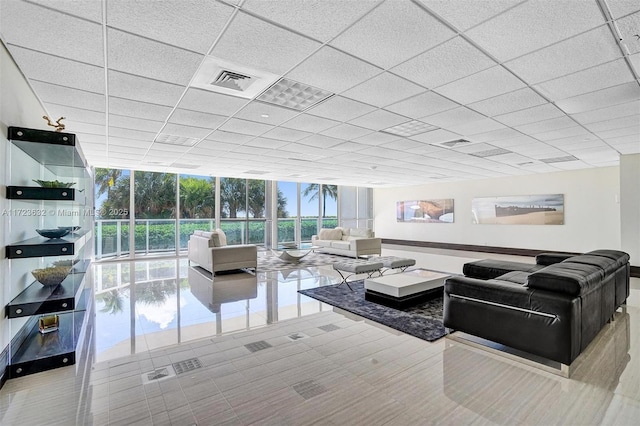 living room with floor to ceiling windows and a drop ceiling