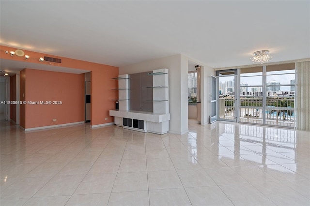 unfurnished living room with an inviting chandelier, light tile patterned floors, and expansive windows