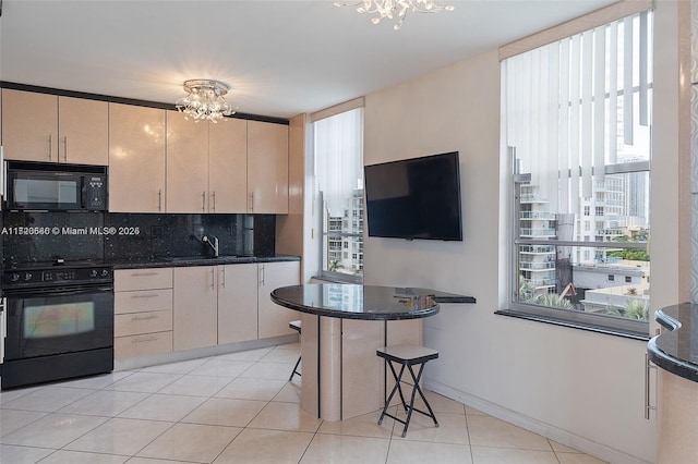 kitchen featuring dark stone counters, black appliances, and an inviting chandelier