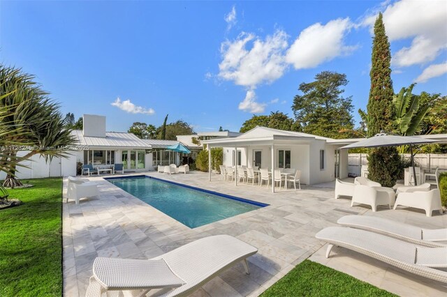 back of property with a fenced in pool, a patio area, and an outbuilding