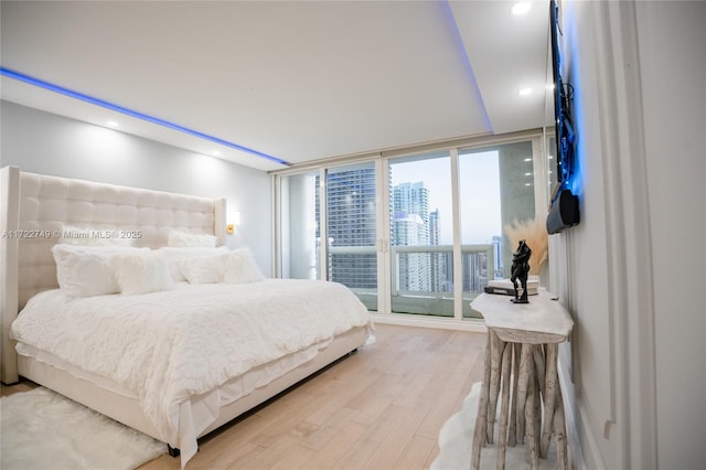 bedroom with multiple windows, hardwood / wood-style floors, access to outside, and floor to ceiling windows