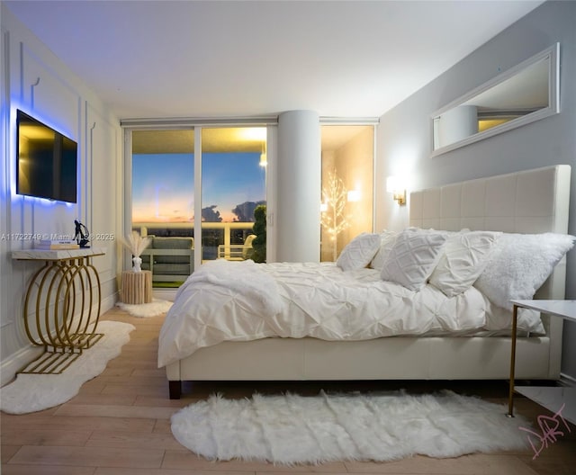 bedroom featuring light hardwood / wood-style flooring and a wall of windows