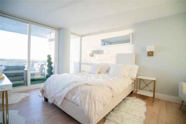 bedroom with multiple windows, a wall of windows, and light wood-type flooring