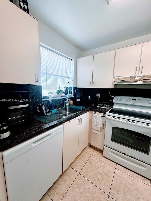 kitchen featuring backsplash, white appliances, sink, light tile patterned floors, and white cabinets