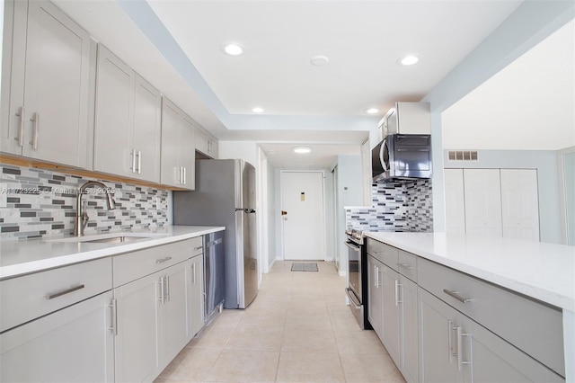 kitchen featuring decorative backsplash, sink, light tile patterned floors, and appliances with stainless steel finishes