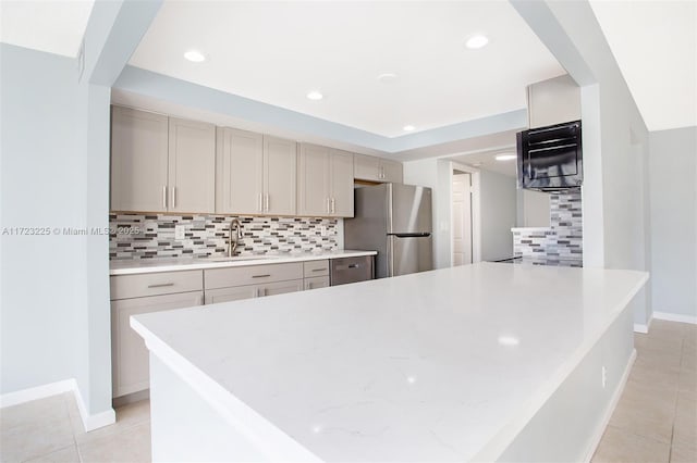 kitchen featuring decorative backsplash, light tile patterned flooring, sink, and stainless steel refrigerator