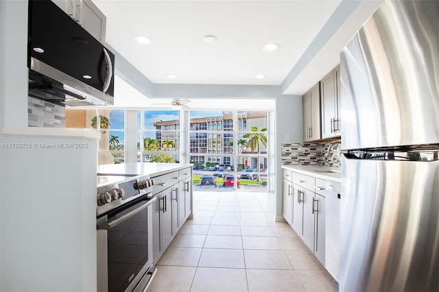 kitchen with light tile patterned floors, backsplash, stainless steel appliances, and gray cabinets