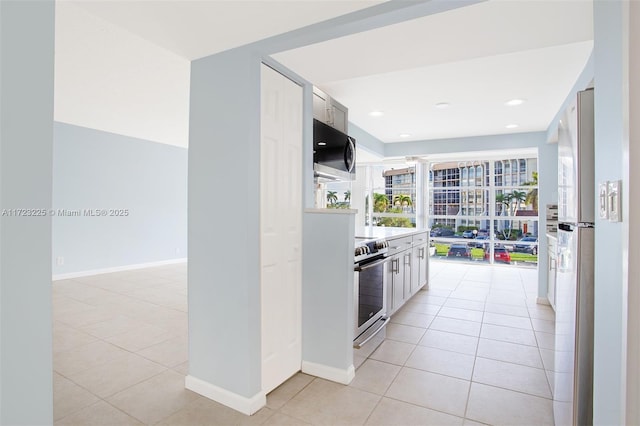 kitchen with white cabinets, light tile patterned flooring, electric range, and fridge