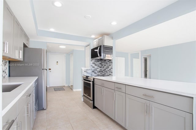 kitchen with gray cabinetry, sink, stainless steel appliances, decorative backsplash, and light tile patterned floors