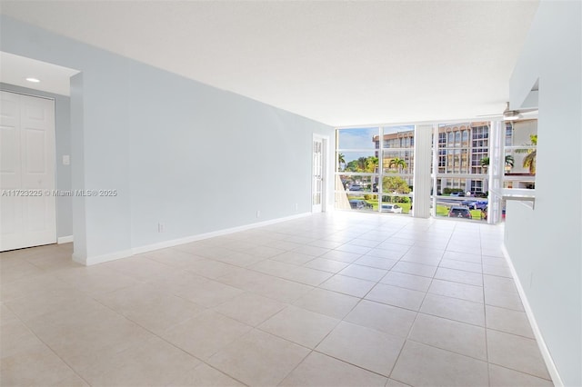 tiled empty room featuring ceiling fan and floor to ceiling windows