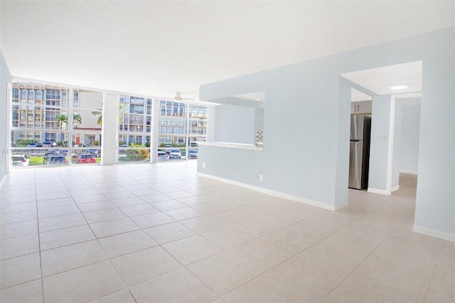 tiled spare room with expansive windows and ceiling fan