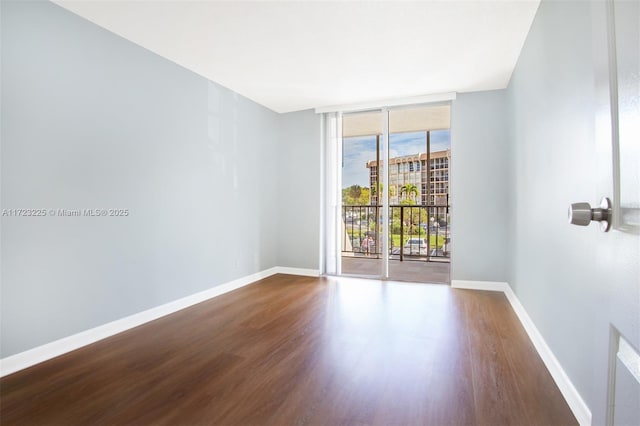 unfurnished room featuring hardwood / wood-style flooring and a wall of windows