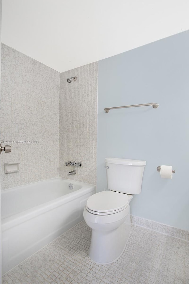 bathroom featuring tile patterned flooring, toilet, and tiled shower / bath