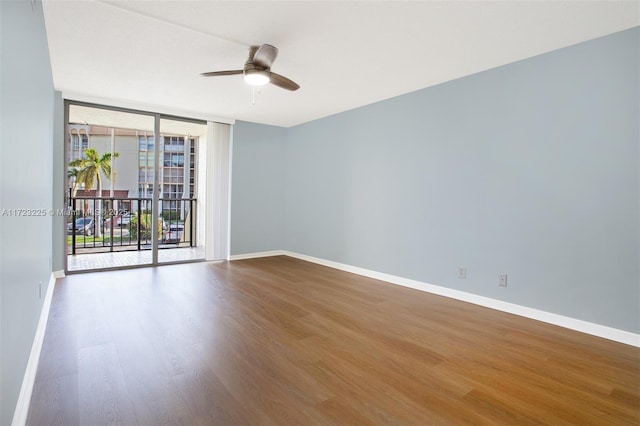 empty room featuring hardwood / wood-style flooring, expansive windows, and ceiling fan