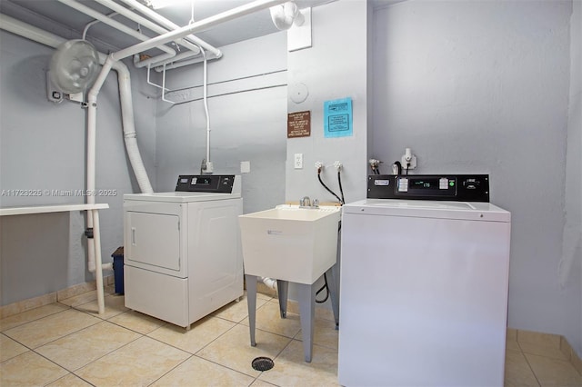 clothes washing area with washer and dryer, light tile patterned floors, and sink