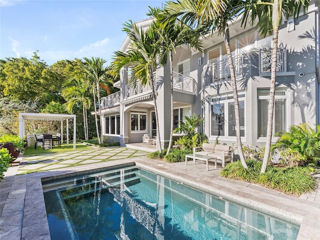 rear view of property featuring a balcony, a patio area, and a hot tub