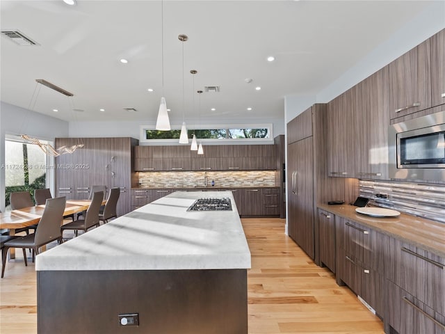 kitchen featuring a center island, decorative backsplash, appliances with stainless steel finishes, and pendant lighting