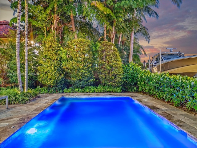 pool at dusk with a patio area