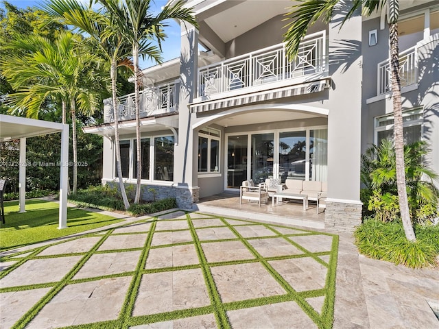 rear view of property featuring a balcony and a patio