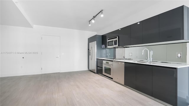 kitchen featuring light wood-type flooring, sink, appliances with stainless steel finishes, and track lighting