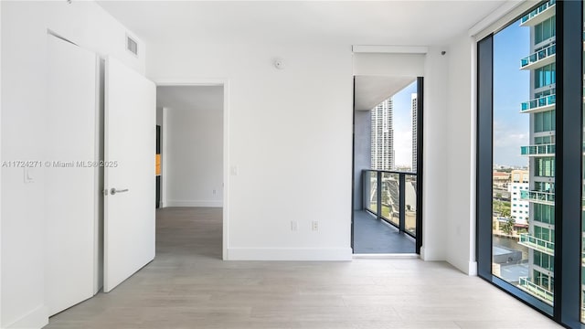 spare room featuring floor to ceiling windows and light wood-type flooring