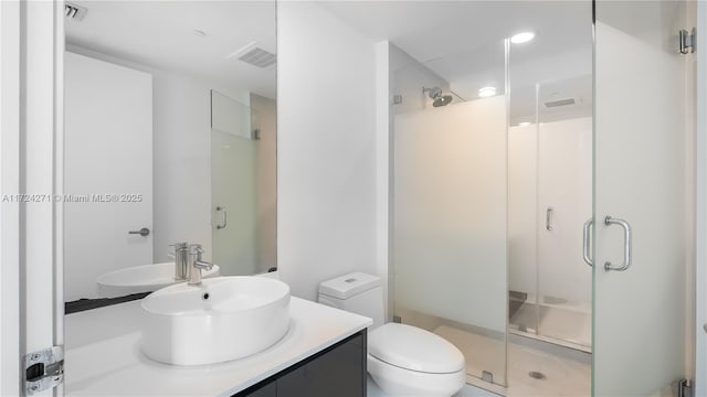 bathroom with vanity, toilet, and a shower with shower door