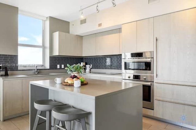 kitchen featuring a breakfast bar, a center island, sink, decorative backsplash, and stainless steel double oven