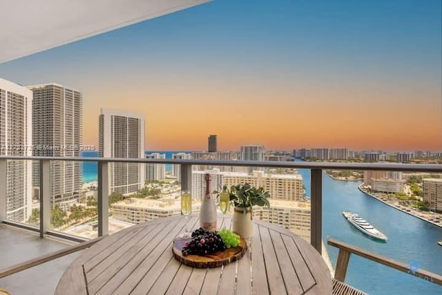 balcony at dusk featuring a water view