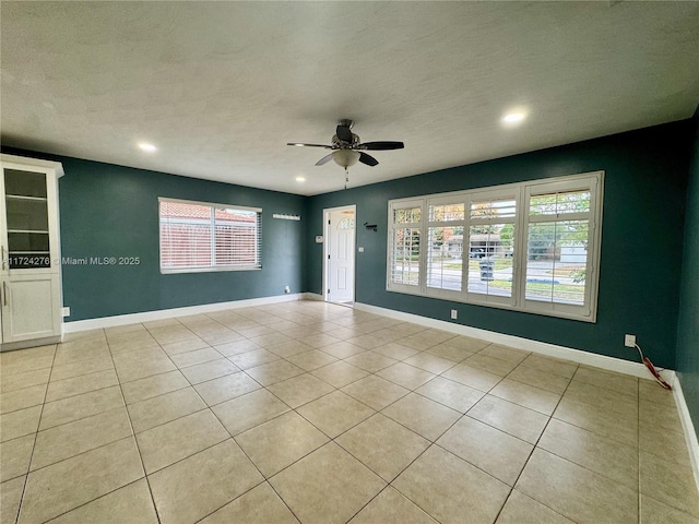 empty room with light tile patterned floors, a textured ceiling, and ceiling fan