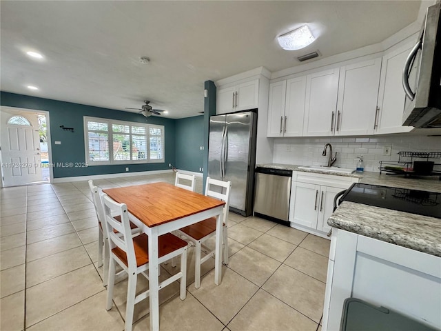 kitchen with light tile patterned floors, light stone counters, white cabinetry, and appliances with stainless steel finishes