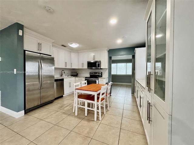 kitchen featuring white cabinets, sink, light tile patterned flooring, a kitchen bar, and stainless steel appliances