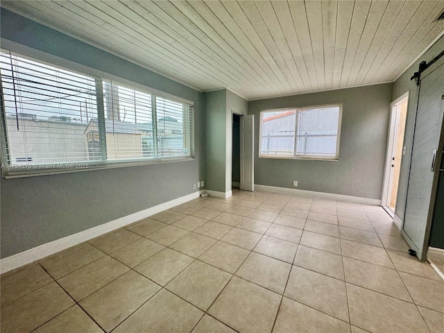 unfurnished room with light tile patterned floors, a barn door, and wooden ceiling