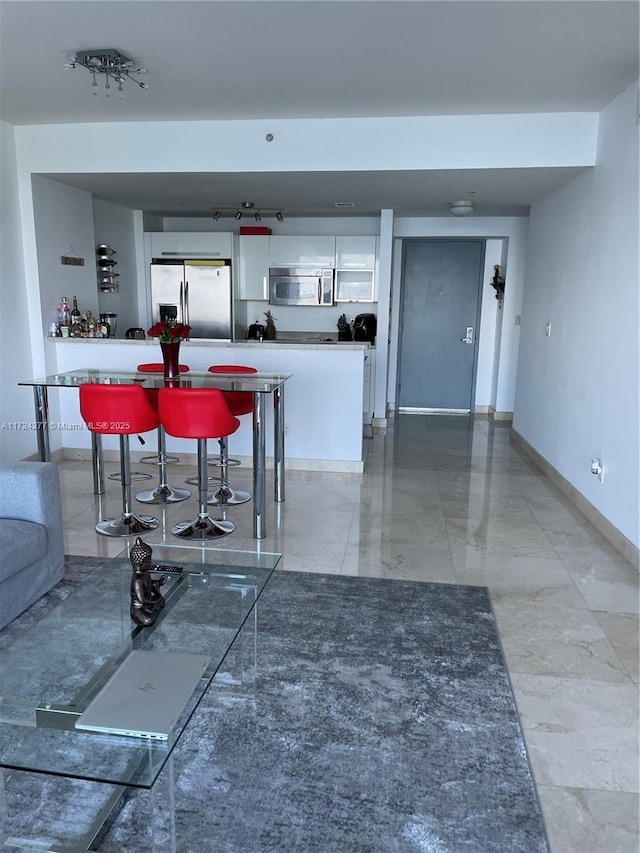 kitchen with a breakfast bar, appliances with stainless steel finishes, and white cabinetry