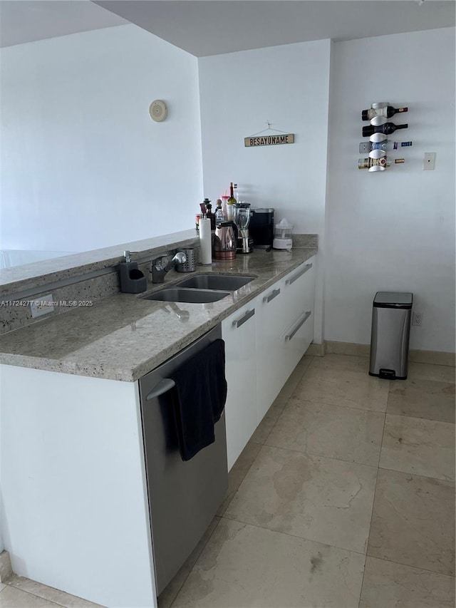 kitchen featuring light stone counters, dishwasher, white cabinets, and sink