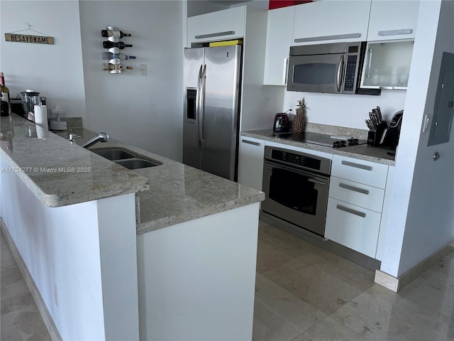 kitchen with appliances with stainless steel finishes, light stone counters, white cabinetry, and sink