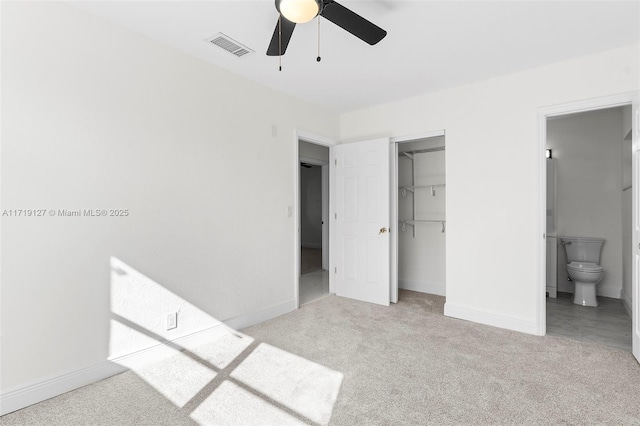 unfurnished bedroom featuring ensuite bath, ceiling fan, a closet, and a spacious closet