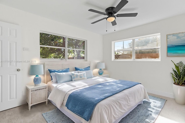 carpeted bedroom featuring multiple windows and ceiling fan