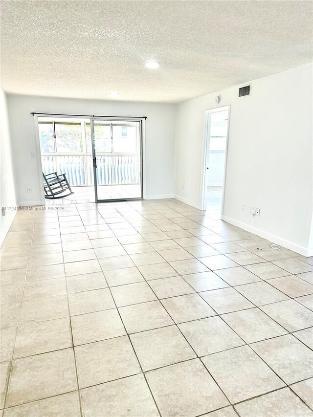 tiled empty room featuring a textured ceiling