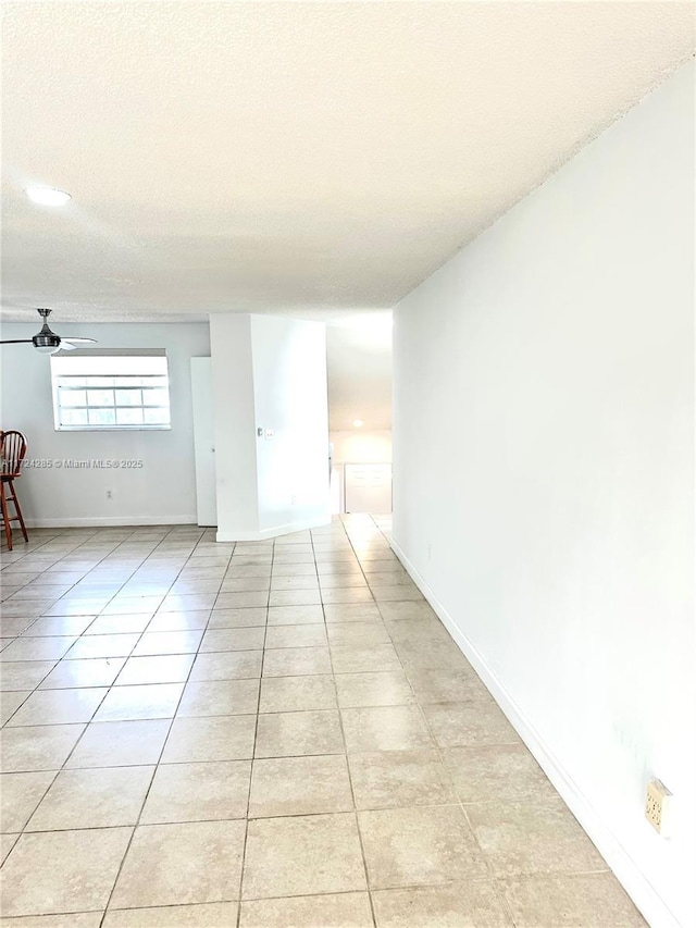 empty room with light tile patterned floors, a textured ceiling, and ceiling fan